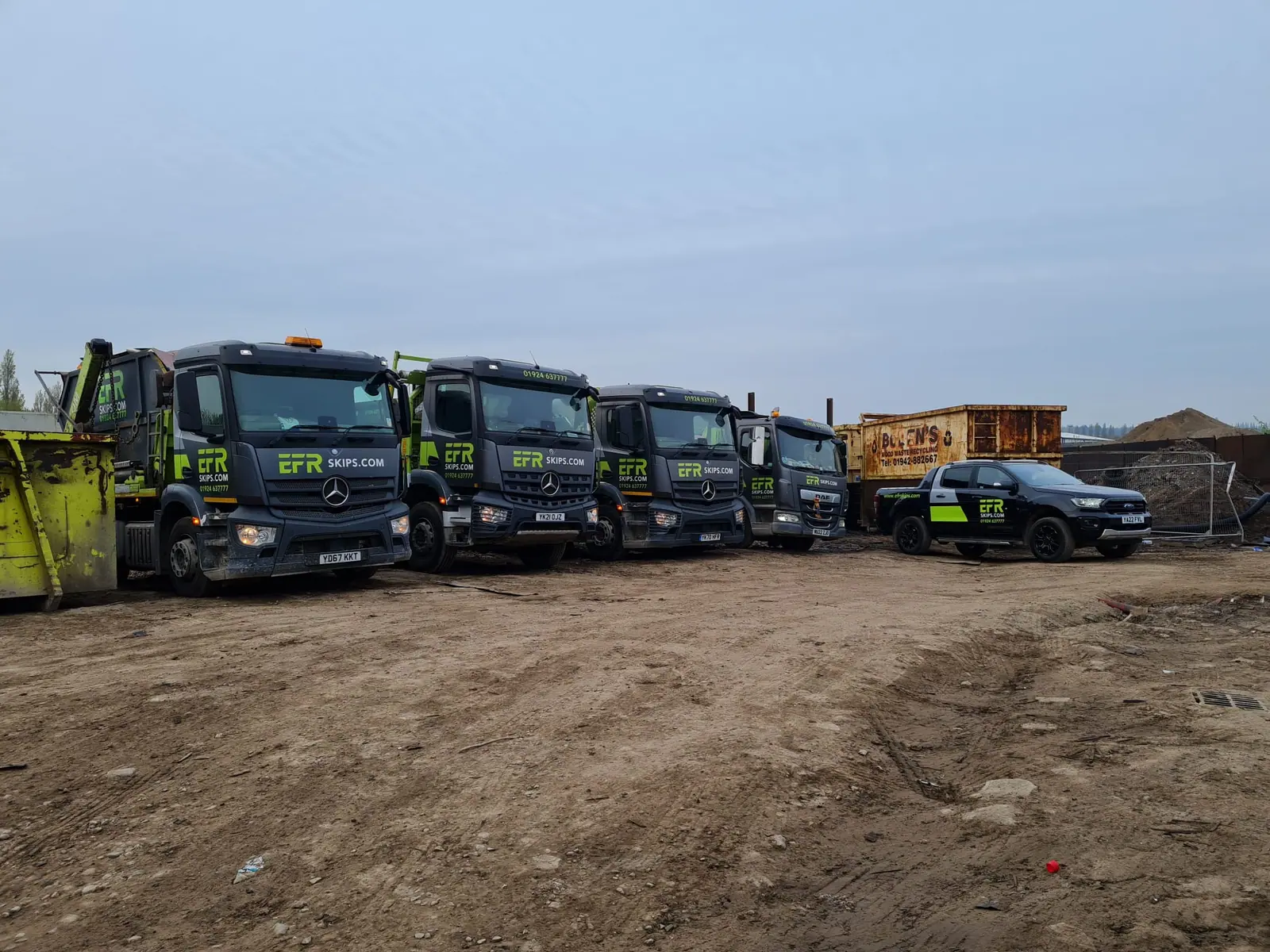 Skip lorries loaded and lined up in a recycling yard at the start of the day